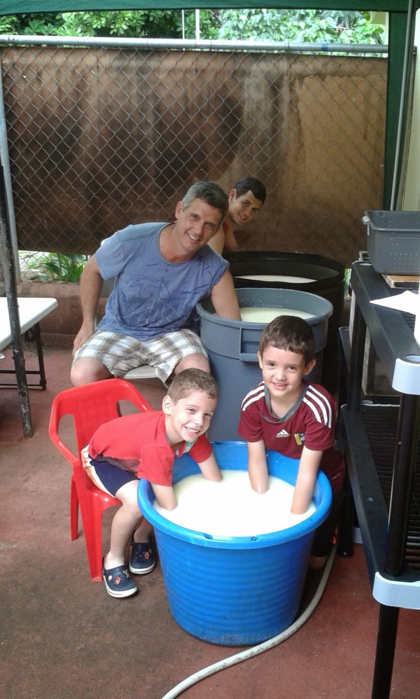 Un adulto y tres niños sonríen alrededor de una tina de leche en el garaje de la casa